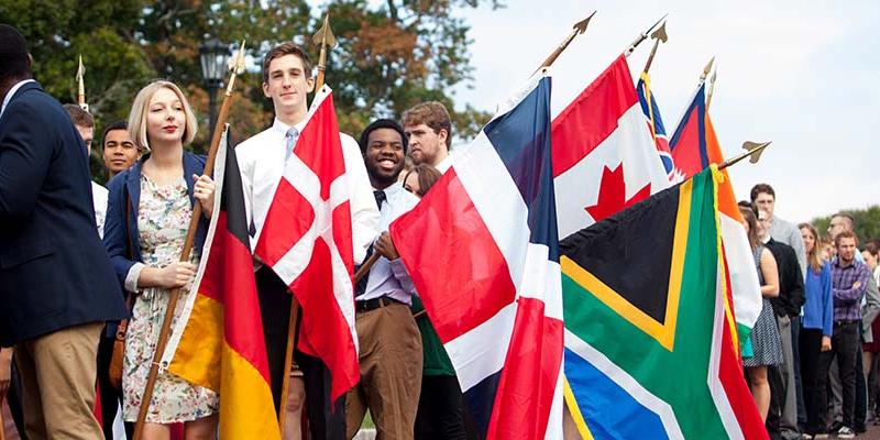 Bryn Athyn College Students processing on Charter Day holding international flags