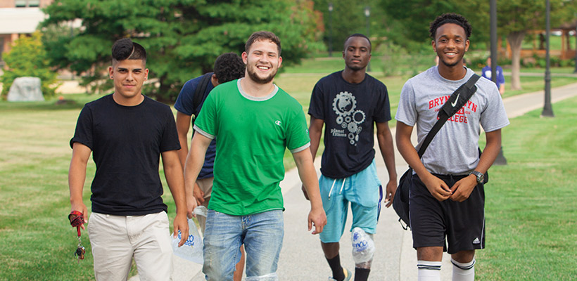 four male students walking near the residence halls