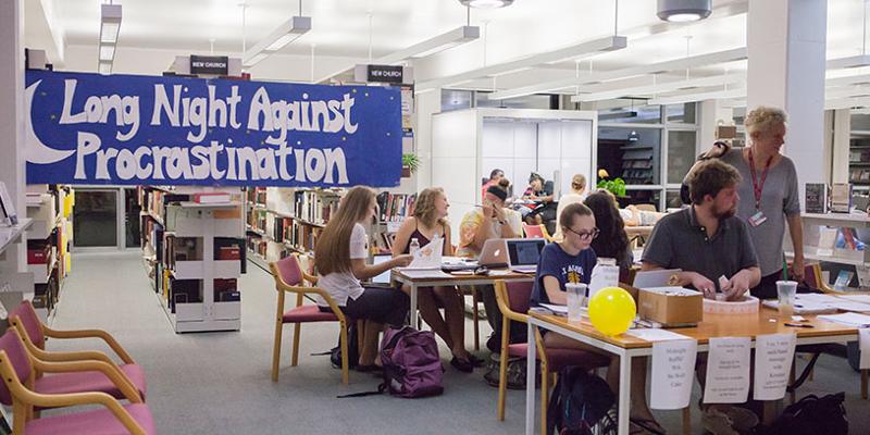 Bryn Athyn College students and support teachers in the library in front of a large blue banner for the long night against procrastination event.students working on laptops in librarystudent receiving a massagestudent working with teacher on laptop