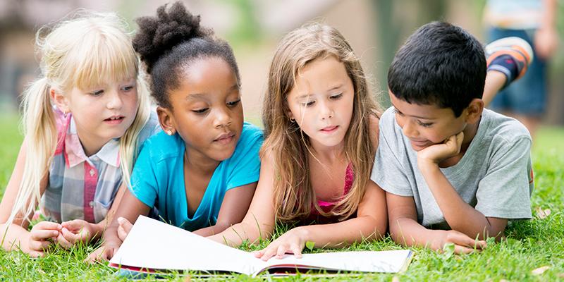 Four children reading in the grass