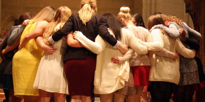 girls lacrosse team embraces in a group hug