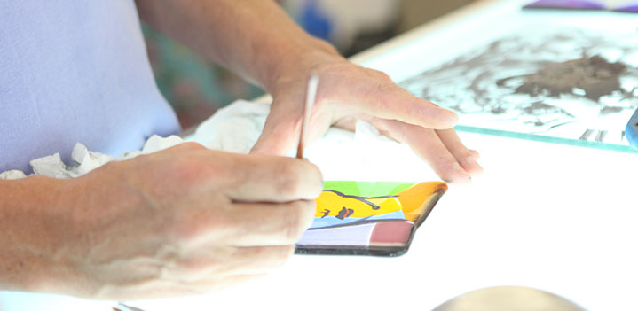 Student works with stained glass on a lit table