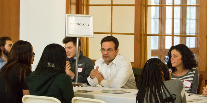 Bryn Athyn College students meet with professionals in the great hall, talking about various careers at tables with white table cloths