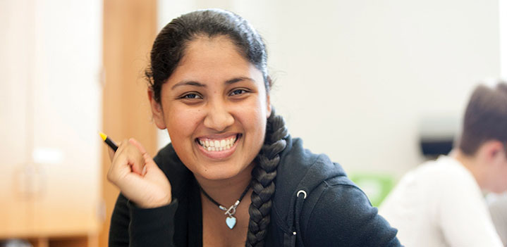 Student smiles at the camera during a classroom assignemtn