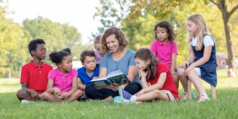 A teacher reads allowed, surrounded by children