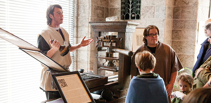 Student demonstrates a printing press to Glencairn visitors
