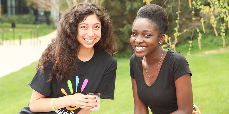 Students smile sitting outside the Brickman Bean at an outdoor barbecue event