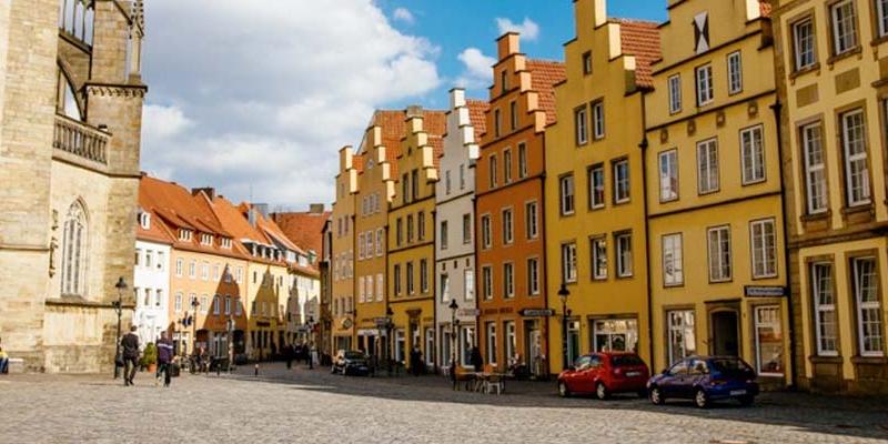 A cobblestone street and a row of orange, yellow, and white homes in Osnabruk, Germany